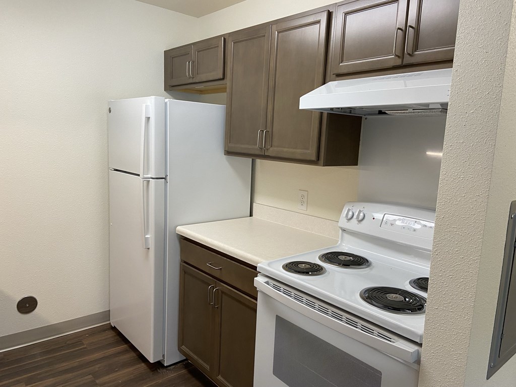 a kitchen with a white stove and refrigerator and wooden cabinets